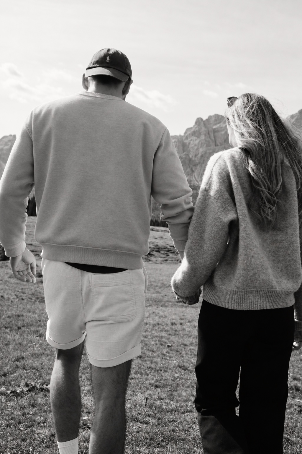 Kim und Marvin halten Händchen vor einer Berglandschaft.